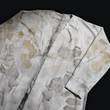 A light-colored long-sleeved cardigan, its fabric delicately patterned with eucalyptus leaves, a testament to the beauty of nature's artistry. The cardigan rests against a dark background, capturing the quiet elegance of a forest clearing.